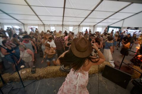 A woman in a cowboy hat dances in front of the stage as the crowd fills the marquee.