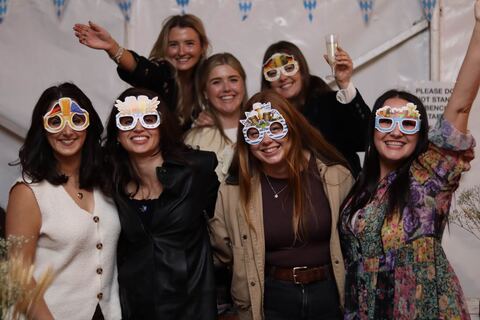 A group of friends in novelty beer glasses pose for the camera.