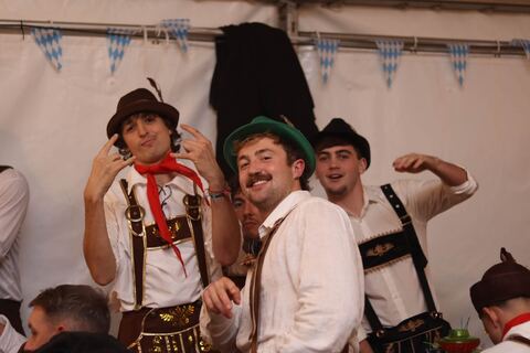 Friends in lederhosen and feathered hats strike a pose under blue and white bunting.